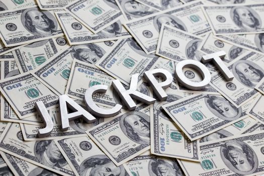 The word JACKPOT laid with aluminium letters on the US dollar banknotes background - with selective focus and diagonal composition.