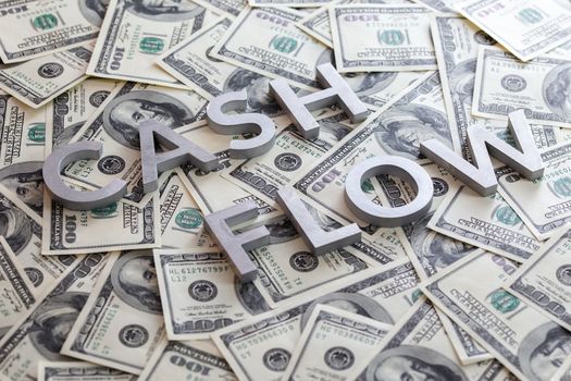 The word CASH FLOW - fear of missing out - laid with aluminium letters on the US dollar banknotes background - with selective focus and diagonal composition.
