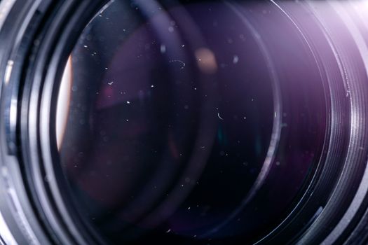 Dust particles in camera lens closeup shot with selective focus and blur. Large front element of professional objective.