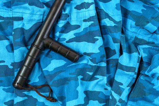 black rubber baton on blue urban russian riot police camouflage flat lay top-down perspective.