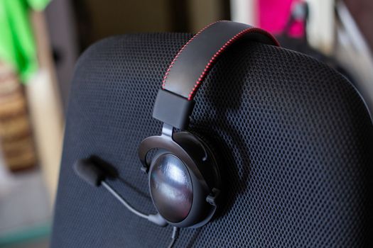 black headset on backrest of empty computer chair with air mesh upholstery.