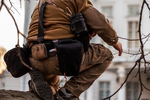 Professional extreme photographer belt pouch system gear in action. Sneaky photoshoot on the fence of private white building.