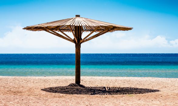 wooden beach umbrella on the shore without people of the Red Sea in Egypt during quarantine