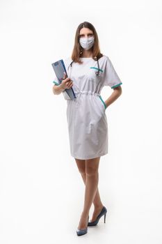 Girl in medical clothes and mask posing with tablet on white background