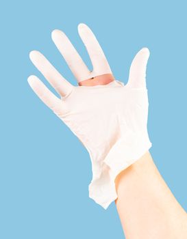 broken white latex surgeon medical glove on caucasian hand isolated on blue monocolor background.