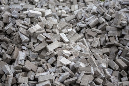 Pile of dismounted gray modern urban pavement bricks with selective focus. Result of russian government corruption in city infrastructure renovation. Piles hidden outside of city - in suburbs wasteland.