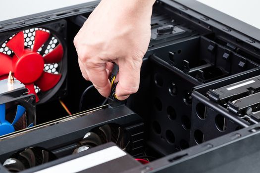 hand plugging aux power connector to the video card while maintenance personal computer hardware with selective focus closeup