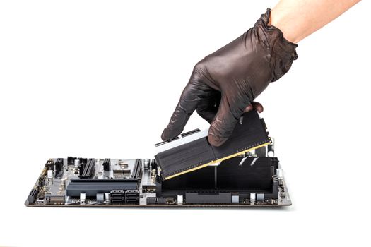 hand in black glove installing memory module with heatsink in pc motherboard isolated on white background with selective focus