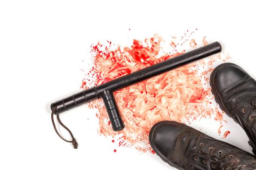 Bloody russian police rubber tonfa baton in blood spatter and pair of black boots isolated on white background in top-down flat lay perspective. Natural human blood used.