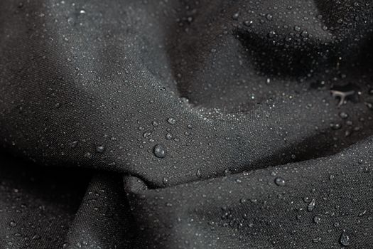 dark gray waterproof hydrophobic cloth closeup with water drops selective focus background.