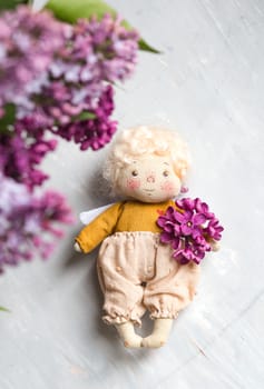 Little golden-haired angel in the blue, pink, purple, violet lilac flowers. Handmade toy in violet lilac colors.