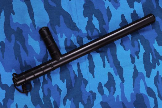 black rubber baton on blue urban russian riot police camouflage flat lay top-down perspective.