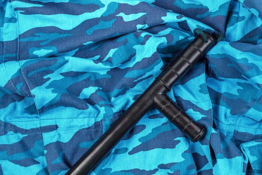 black rubber baton on blue urban russian riot police camouflage flat lay top-down perspective.
