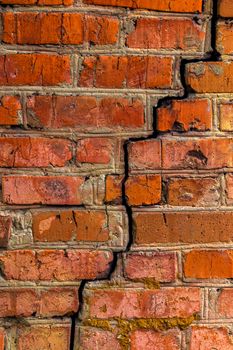 Deep cracked orange brick wall closeup texture and background. Vertical shot.