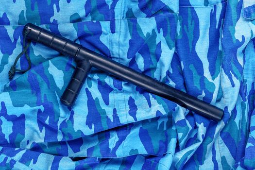 black rubber baton on blue urban russian riot police camouflage flat lay top-down perspective.