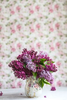 Bouquet of violet lilac in a vintage shabby vase. Still life with blooming branches of lilac in vases. Greeting card mock up.