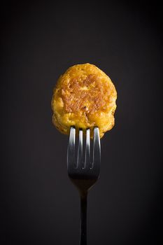 Corn pancakes on a fork on a black background