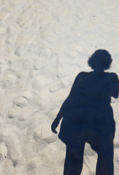 shadow or silhouette of woman or girl in sand at beach