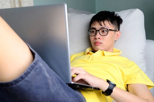 An asian young  man is working from home during Coronavirus or Covid-19 quarantine, coronavirus covid 19 infected patient in coronavirus covid 19 quarantine room using computer.