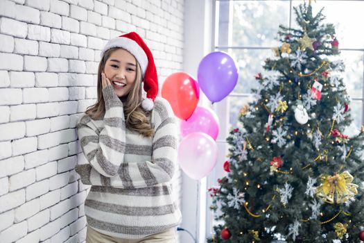 Portrait cute Asian young woman in costume Christmas and wear red santa claus hat with smile and theme Christmas background in the home, copy space. Teen woman with celebrate Christmas.