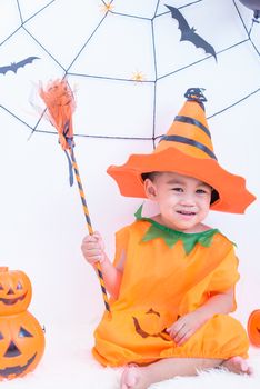 Funny happy little cute child boy in Halloween costume with orange pumpkin Jack with Cobweb in-home with Halloween party on white wall background, Happy Halloween day concept