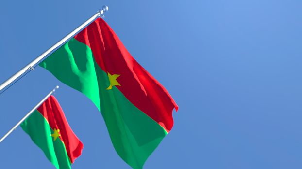 3D rendering of the national flag of Burkina Faso waving in the wind against a blue sky