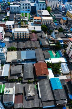 View from the high floor of the streets of Bangkok. Tall buildings and roofs of small houses. City landscape.