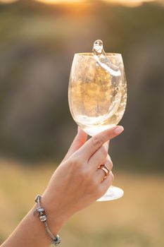 Girl churns wine in a glass at sunset