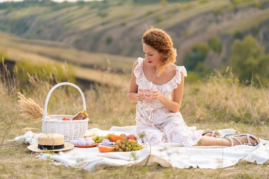 Beautiful girl on a picnic in a picturesque place. Romantic picnic.