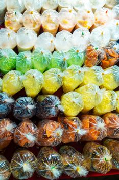 Colored desserts in plastic bags at a street food market in Asia. Unusual Asian food