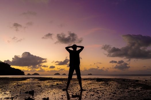 Silhouette of a man on the beach at sunset. Man rejoices meets the sunset.