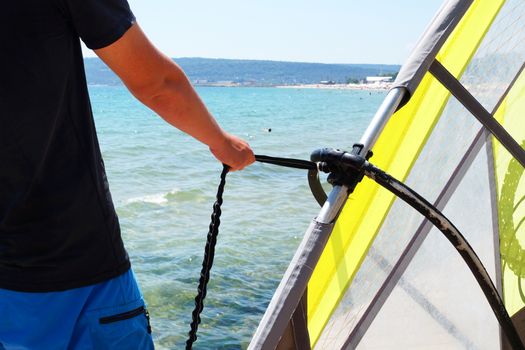 man holding windsurf sail for rope close up