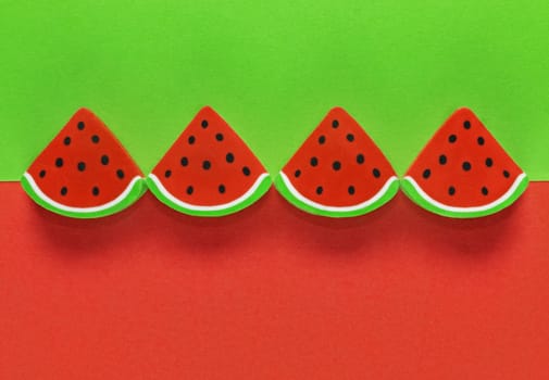 A group of erasers shaped like sliced watermelon in a row on a colored background ,simple composition 