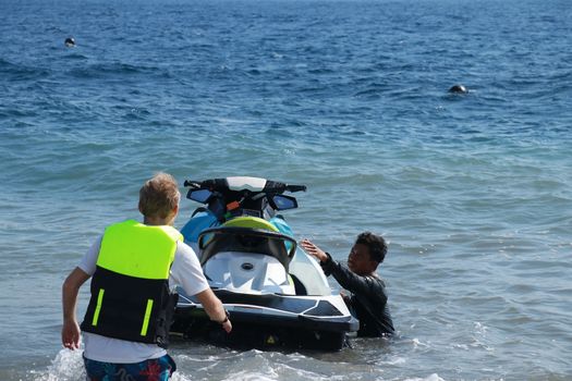 Man Take a water bike for ride. Wwatercrafts and wave runners are having fun on a sunny day. The instructor explains to the customer how to drive a jet ski.