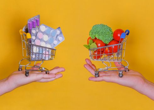 Hands holding shopping carts with vegetables and tablets on a yellow background, the concept of choosing healthy food and disease