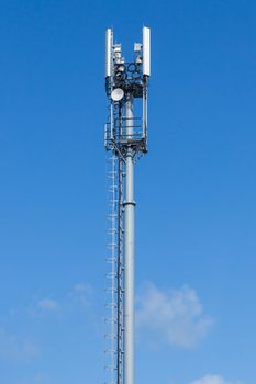 Gray pipe telecommunication tower on blue sky background, Vertical telephoto shot above horizon line.