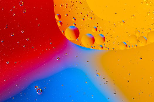 Oil on water flat colorful macro abstract background photographic image. Red, yellow and blue color,