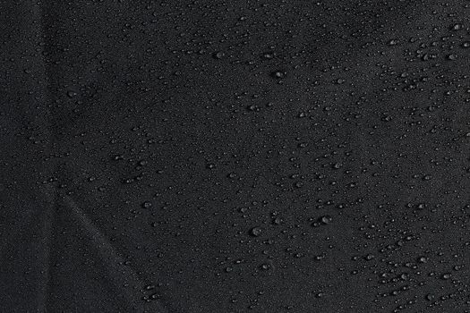 dark gray waterproof hydrophobic flat cloth closeup with water drops background.