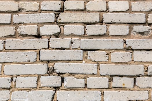 Deep cracked white silicate brick wall closeup texture and background. Horizontal shot.
