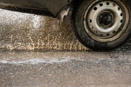 Car moving on wet asphalt with splashes of dirty water. Motion blur technique.