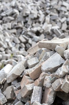 Pile of dismounted gray modern urban pavement bricks with selective focus. Result of russian government corruption in city infrastructure renovation. Piles hidden outside of city - in suburbs wasteland.