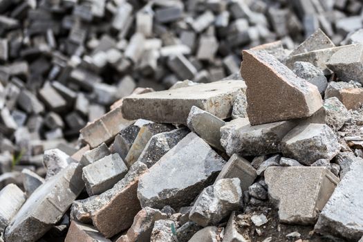 Pile of dismounted gray modern urban pavement bricks with selective focus. Result of russian government corruption in city infrastructure renovation. Piles hidden outside of city - in suburbs wasteland.