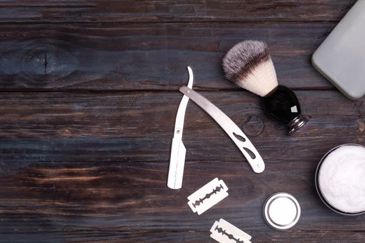 Razor, brush, blades, balsam and shaving foam on a black background.