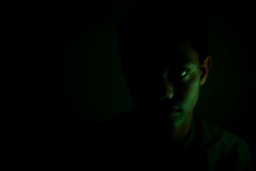 Portrait of young boy staring in dark