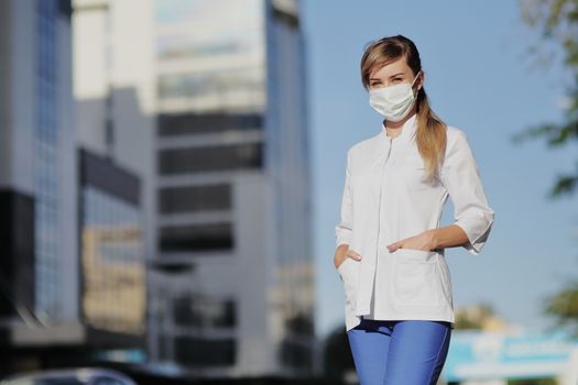 Female doctor, a nurse wearing a protective face mask in the city. Skyscraper, sky. Safety measures against the coronavirus. Prevention Covid-19 healthcare concept. Stethoscope. Woman, girl.
