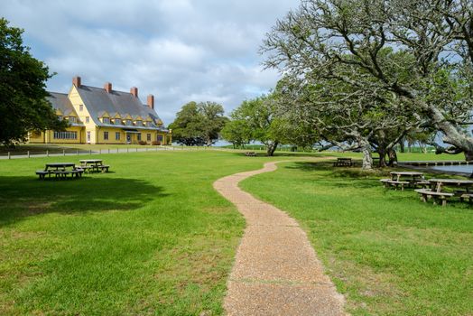 Corolla Park, North Carolina, USA -- June 10, 2020. A wide angle photo of a walking path in Corolla Park with the historic Whalehead museum off to the