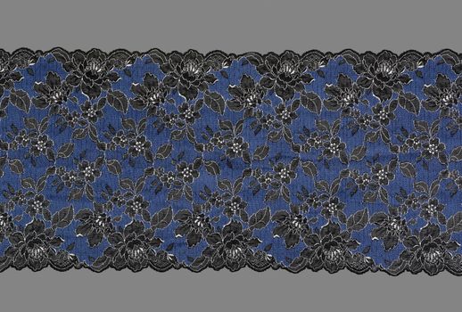 blue and black color straight strip of lace fabric on gray background. Elastic silk nylon braid border. use clothes linen decoration. repeating pattern and interweaving threads. texture for websites