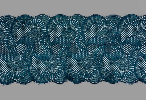 emerald green color straight strip of lace fabric on gray background. Elastic silk nylon braid border. use clothes linen decoration. repeating pattern and interweaving threads. texture for websites