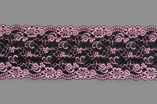 pink black color straight strip of lace fabric on gray background. Elastic silk nylon braid border. use clothes linen decoration. repeating pattern and interweaving threads. texture for websites