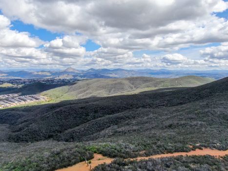 Aerial view of Black Mountain in Carmel Valley, San Diego, California, USA. Green dry mountain during sunny cloudy day with hiking trails, perfect for sport activity an leisure time..